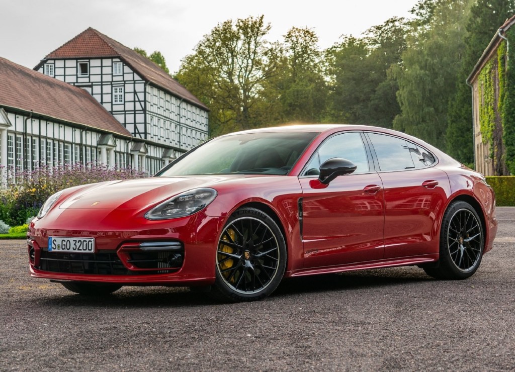 A red 2021 Porsche Panamera GTS parked in a forest village