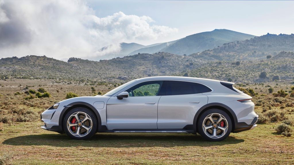 The side view of a white 2021 Porsche Taycan 4S Cross Turismo on a grassy mountain moor