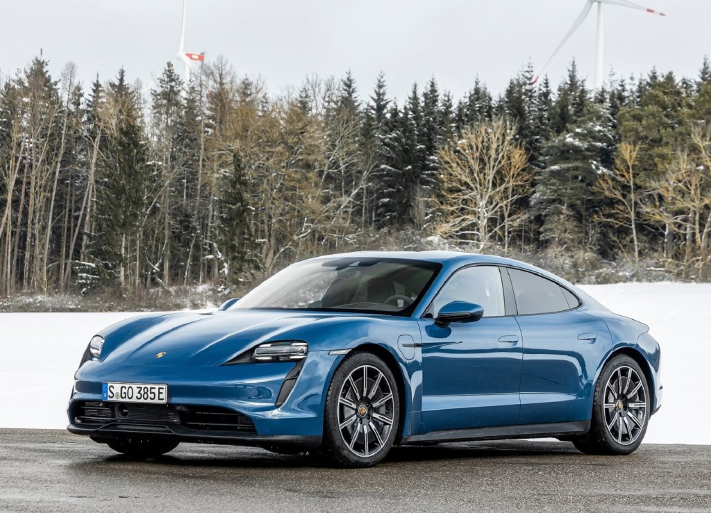 A blue 2021 Porsche Taycan parked by a snowy forest