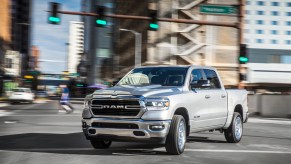 A silver 2021 Ram 1500 Big Horn four-door full-size pickup truck turning in a city intersection