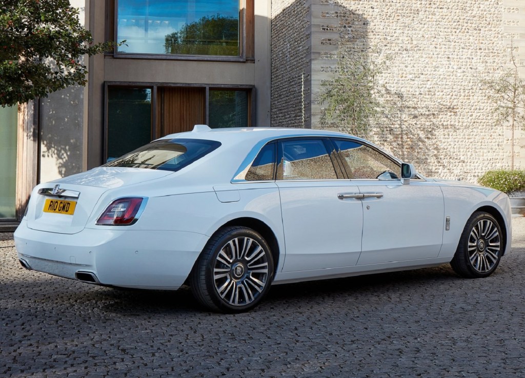The rear 3/4 view of a white 2021 Rolls-Royce Ghost by a stone building