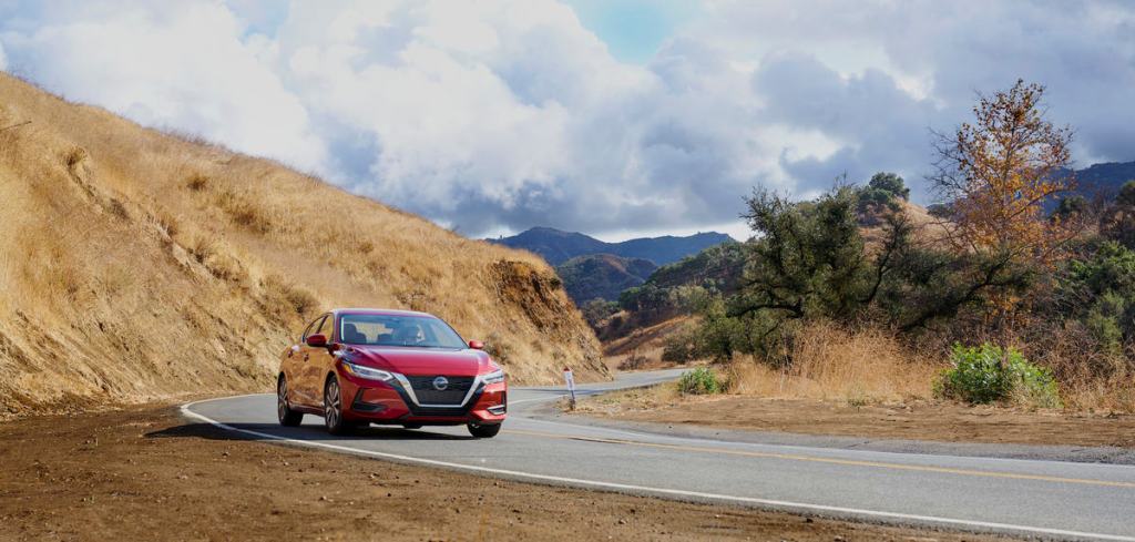 A red 2021 Nissan Sentra driving down a windy road
