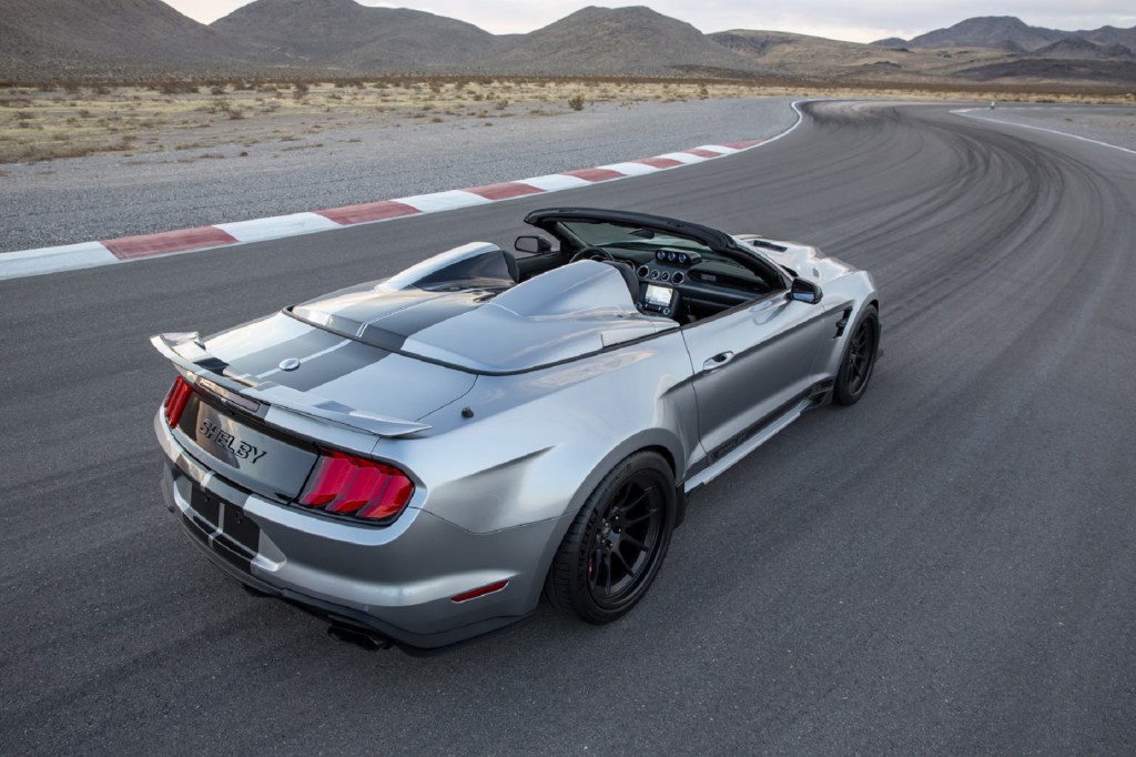 An overhead rear 3/4 view of a silver-with-black-stripes 2021 Shelby Super Snake Speedster on a desert racetrack