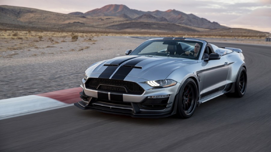 A silver-with-black-stripes 2021 Shelby Super Snake Speedster drives on a desert racetrack