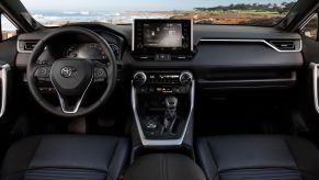 A silver 2021 Toyota RAV4 Hybrid SUV's black dashboard, steering wheel, center stack, and infotainment touchscreen