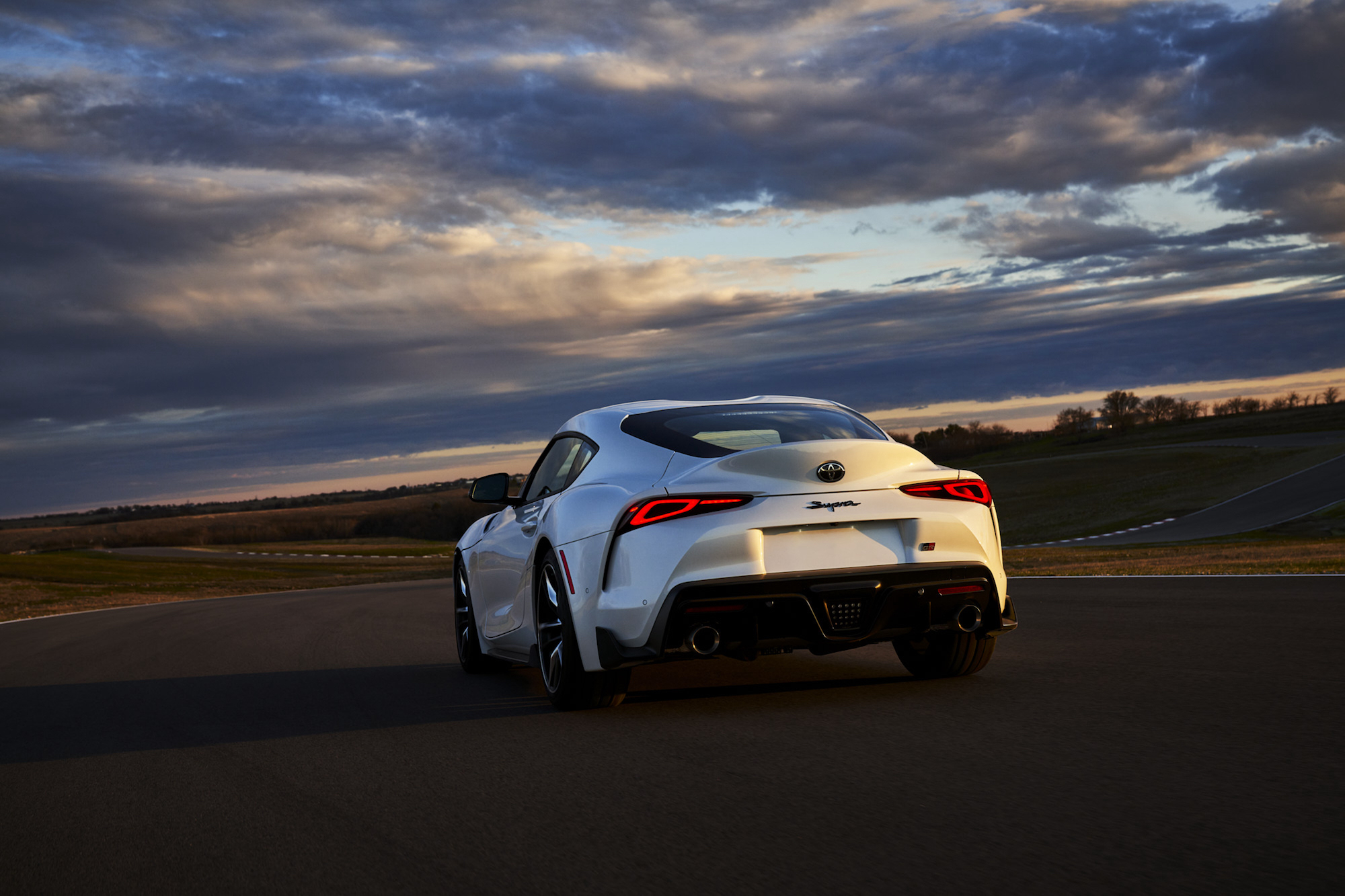 A rear view of a white 2021 Toyota GR Supra 3.0 Premium sitting on a racetrack