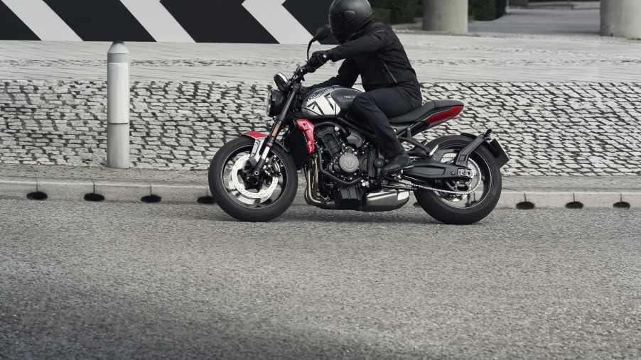 A black-clad rider takes the gray-and-black 2021 Triumph Trident 660 around a street corner