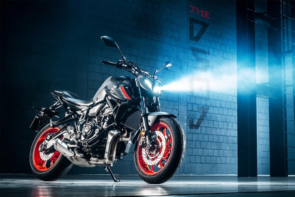 A gray 2021 Yamaha MT-07 with its headlight on in a concrete garage