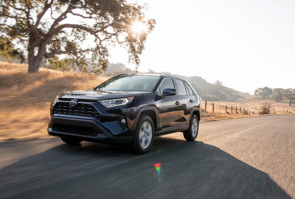 A 2021 Toyota RAV4 Hybrid shown in blue driving down the road