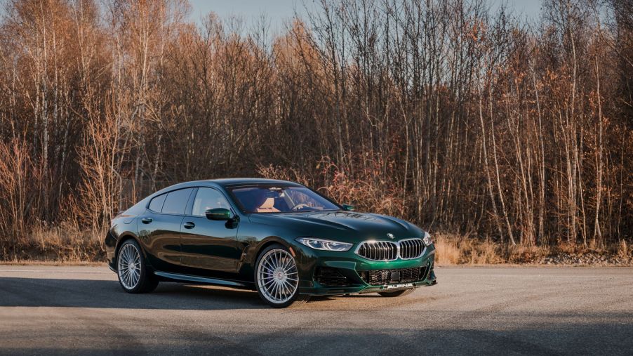 A dark-green 2022 BMW Alpina B8 Gran Coupe parked by a winter-time forest