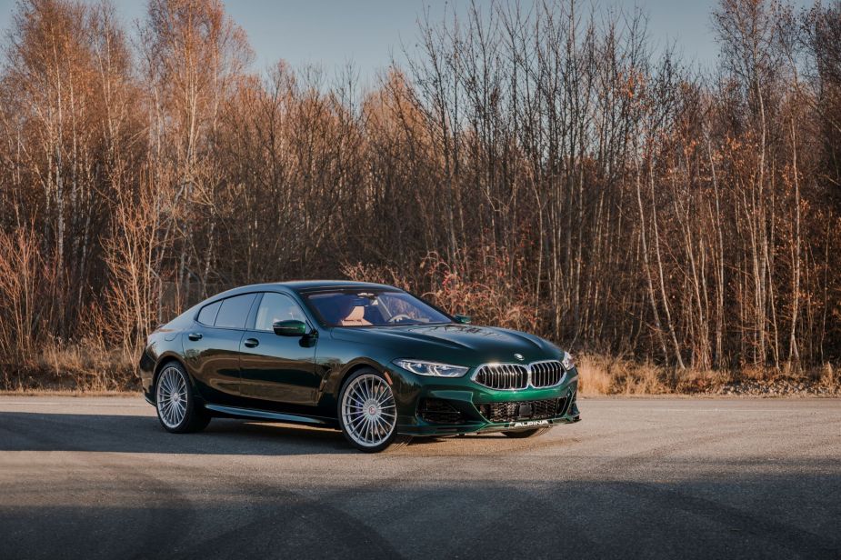 A dark-green 2022 BMW Alpina B8 Gran Coupe parked by a winter-time forest