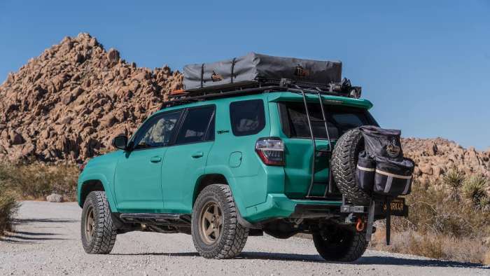 rendering of a teal Toyota 4runner trd pro in the desert with a roof tent