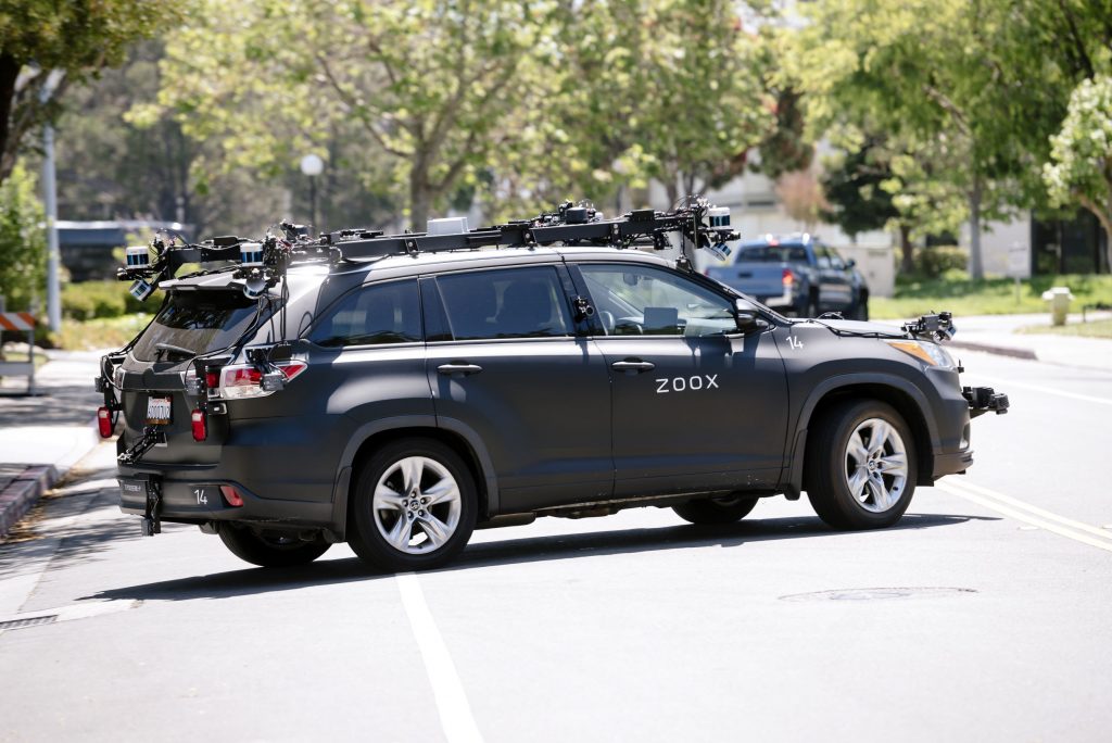 A gray Zoox Inc. autonomous test car driving on a California city street