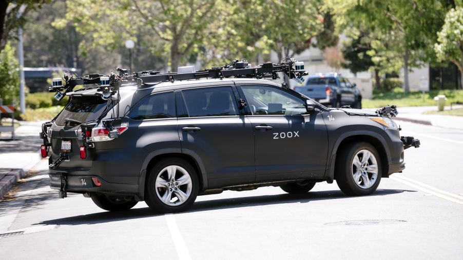 A gray Zoox Inc. autonomous test car driving on a California city street