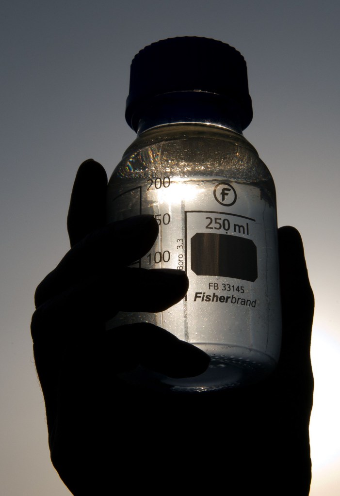 A bottle of Sunfire synthetic fuel held up to the sunlight