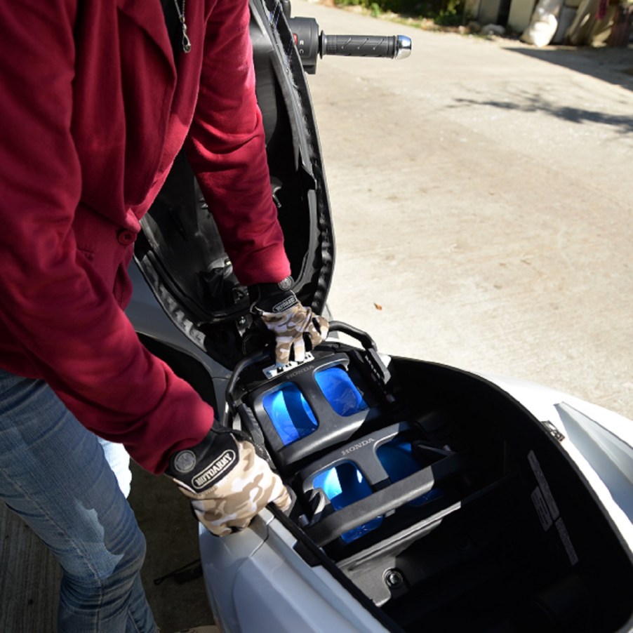 A red-clothed rider swaps the battery on a white electric 2018 Honda PCX bike