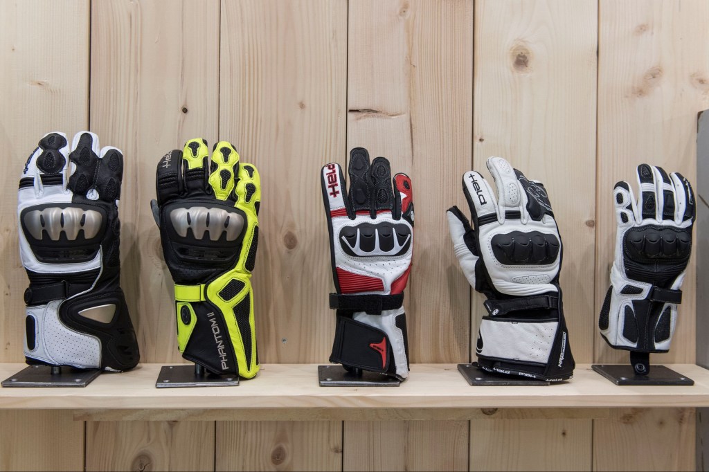 A selection of gauntlet-style motorcycle gloves on display on a wooden stand