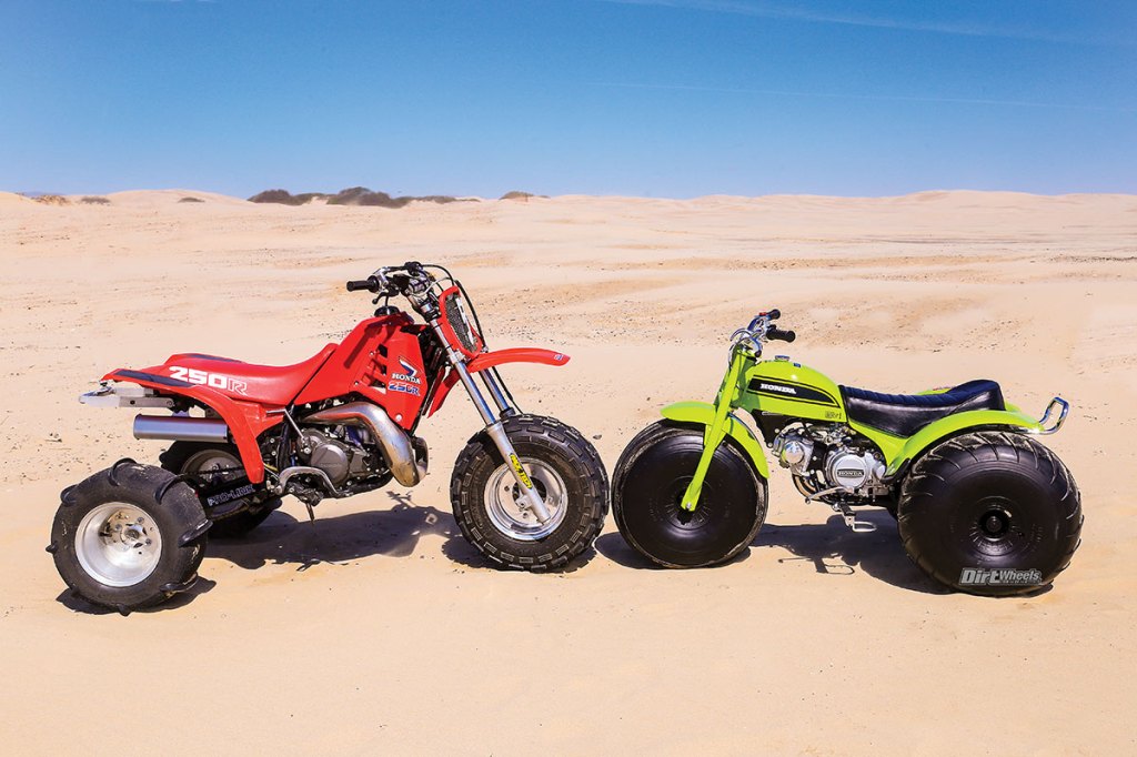 one red and one green three-wheeler ATV on display in the desert
