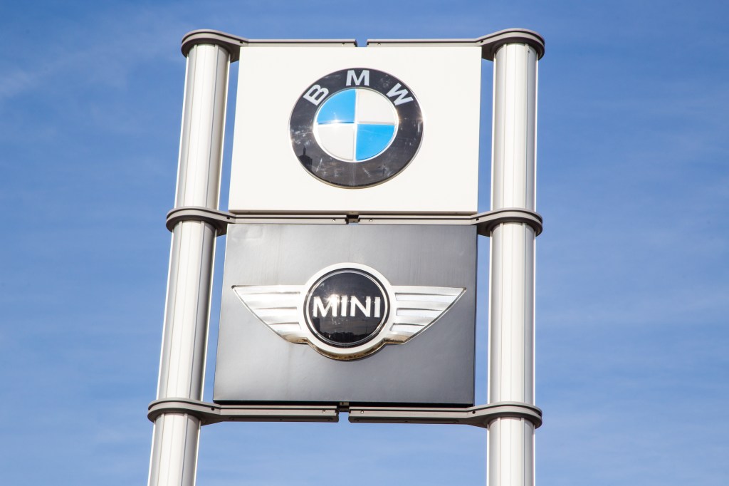 BMW and Mini logos on signs at a car dealership with a blue sky in the background