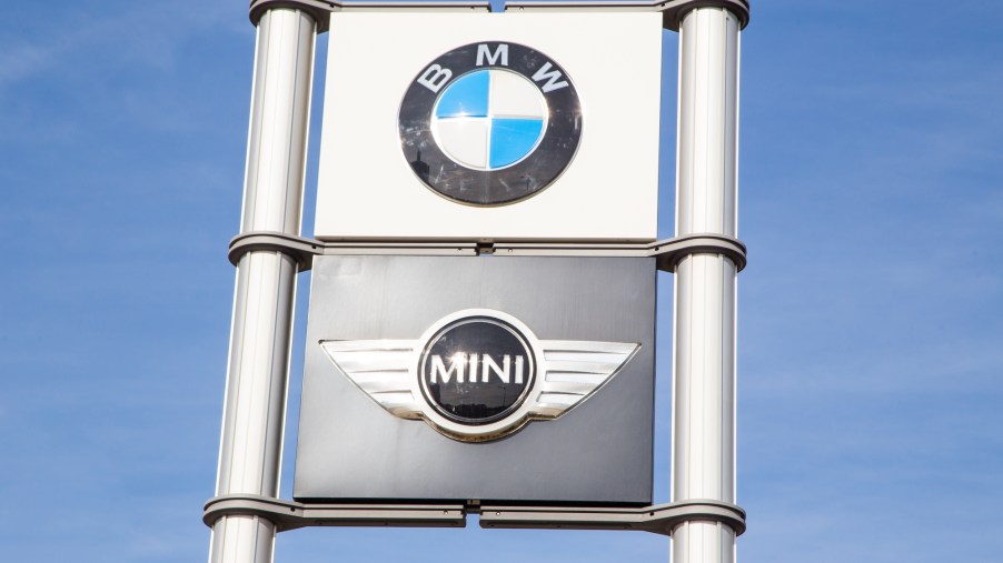 BMW and Mini logos on signs at a car dealership with a blue sky in the background