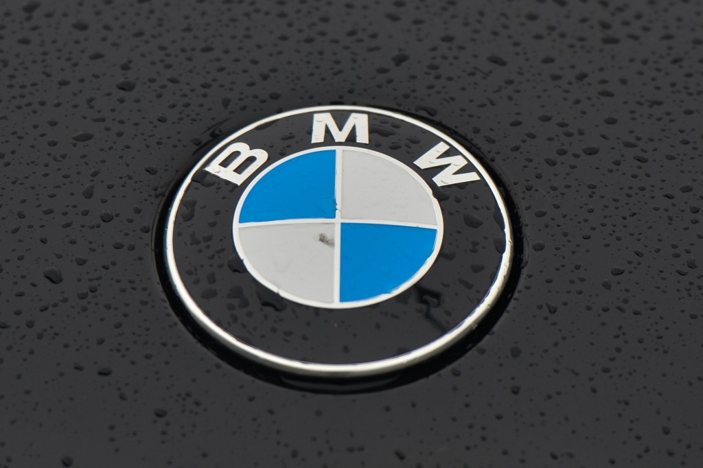 A raindrop-dotted BMW logo on a parked black car