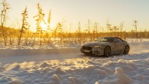 A camouflaged 2022 Mercedes-AMG SL with a red roof undergoing winter testing