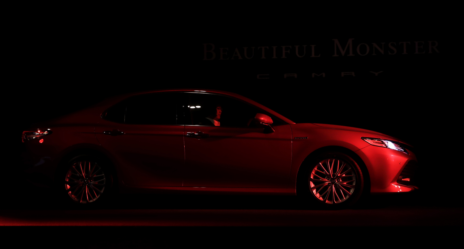 A Toyota Camry sits in the shadows before a launch