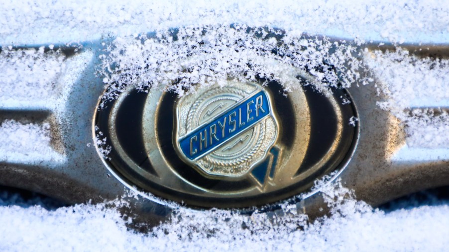A Chrysler car emblem is covered with snow on a car