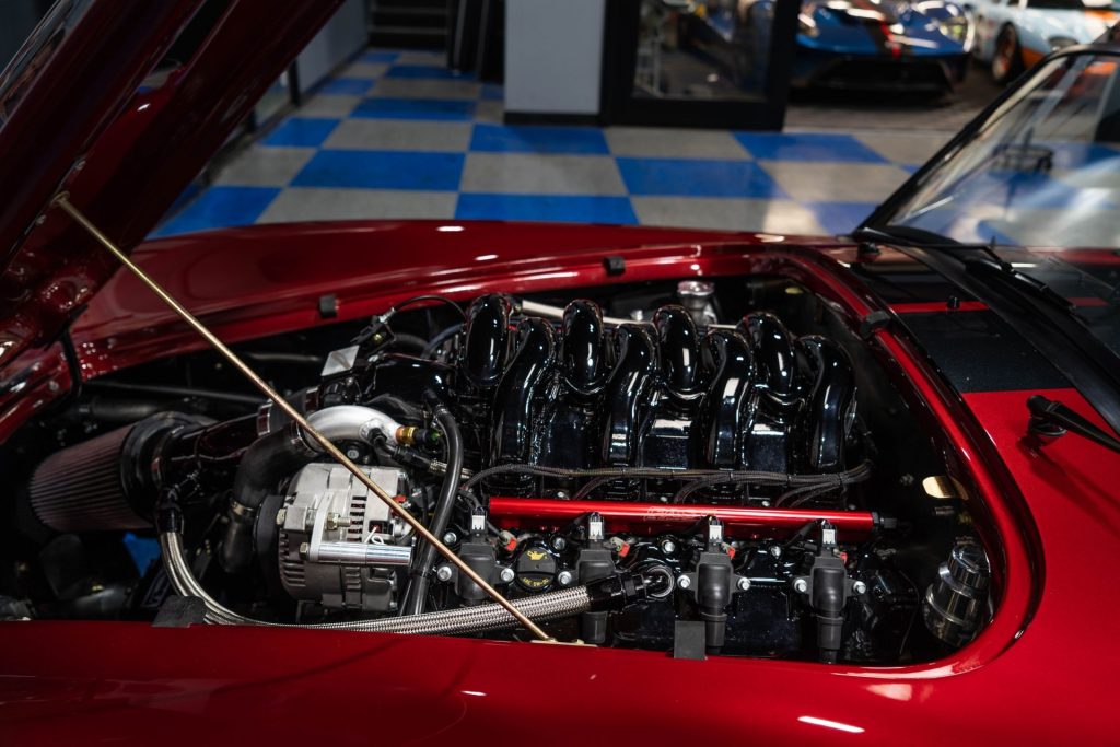 The engine bay of a red-with-black-stripes Superformance MKIII-R with a Ford 7.3-liter Godzilla V8