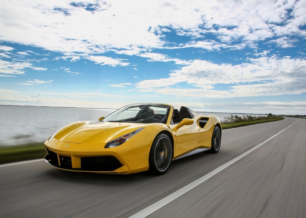 An image of a yellow Ferrari 488 Spider driving down the road.