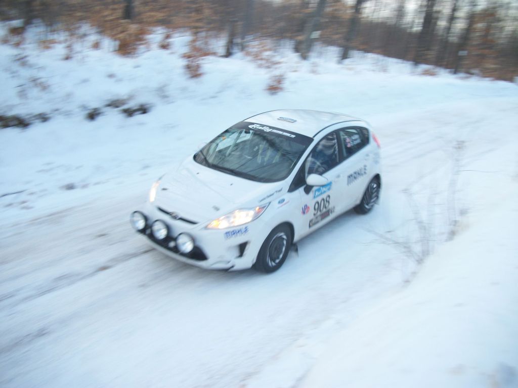 A white Ford Fiesta racing through the snowy forest stage at the 2016 SnoDrift Rally