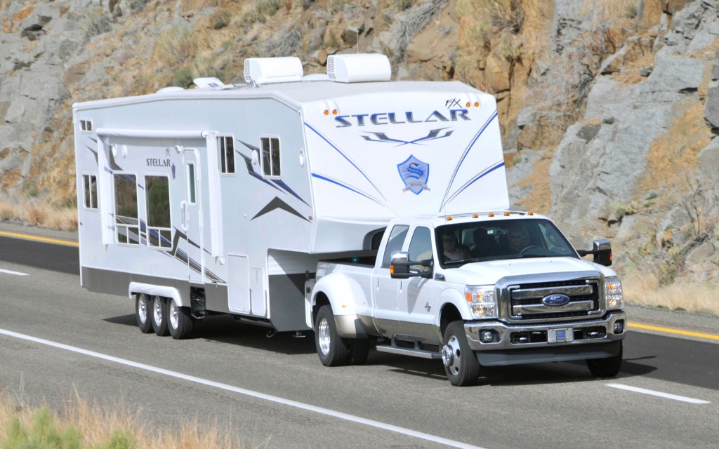 A white Ford F-350 super duty pickup truck towing a fifth-wheel RV