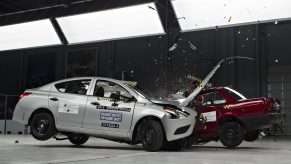 A silver Nissan Versa and a red car colliding during an IIHS crash test