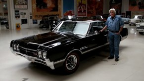 Jay Leno with a black 1966 Oldsmobile 442 in his garage
