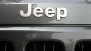Closeup of the Jeep logo across the bumper of a gray Jeep Cherokee