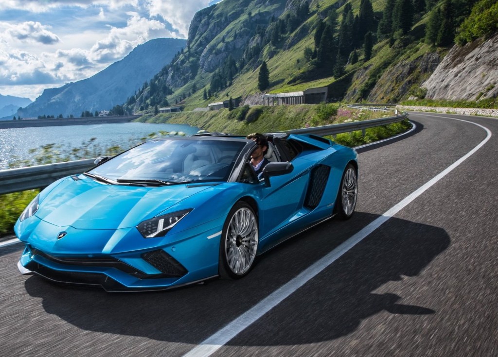 A blue 2018 Lamborghini Aventador driving through the swiss alps with the top down.