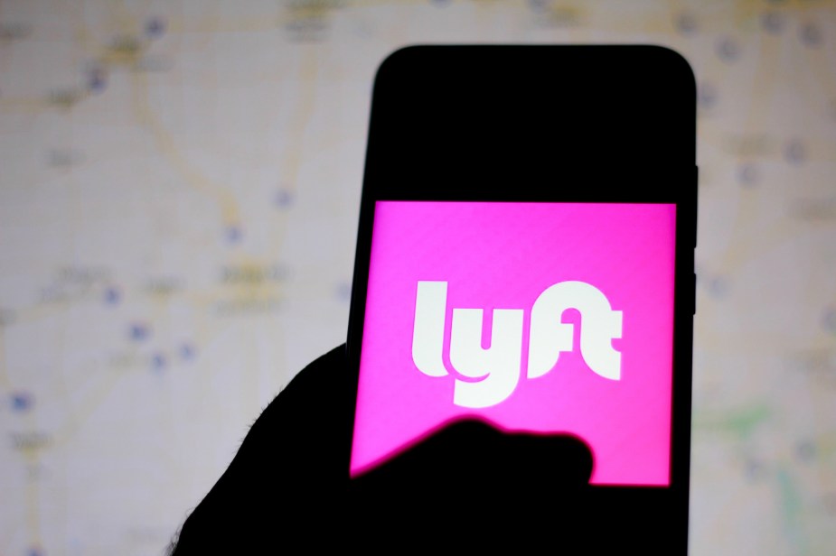 The Lyft logo displayed on a smartphone in a person's left hand