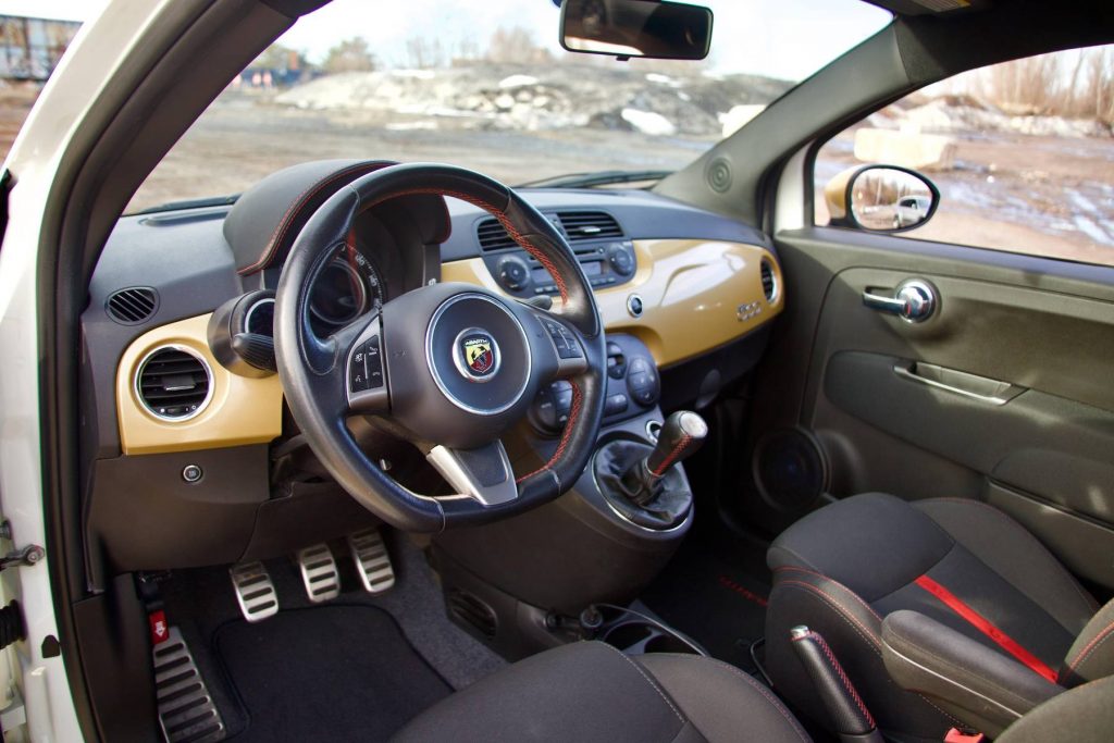 The black-and-red front sport seats and gold-painted dashboard of a modified 2013 Fiat 500 Abarth