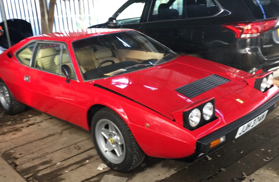 An image of a red Ferrari Dino 308 GT4 parked outdoors.