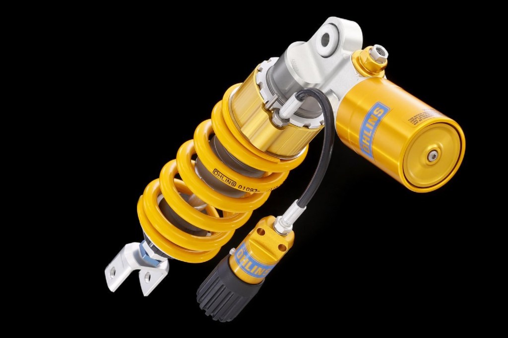 A golden-yellow Ohlins rear motorcycle shock for a 2012 Triumph Street Triple R