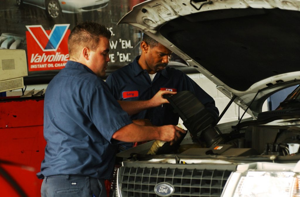 Mechanics Larry Anderson, right, and Brandon Engler change the oil in a car.