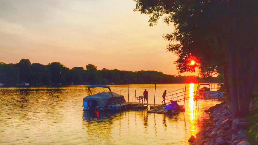 A pontoon boat docked on a lake at sunset