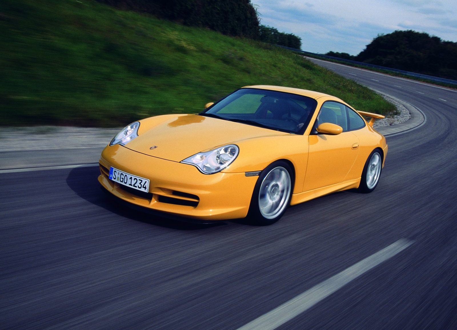 An image of a yellow Porsche 911 GT3 driving on a road.