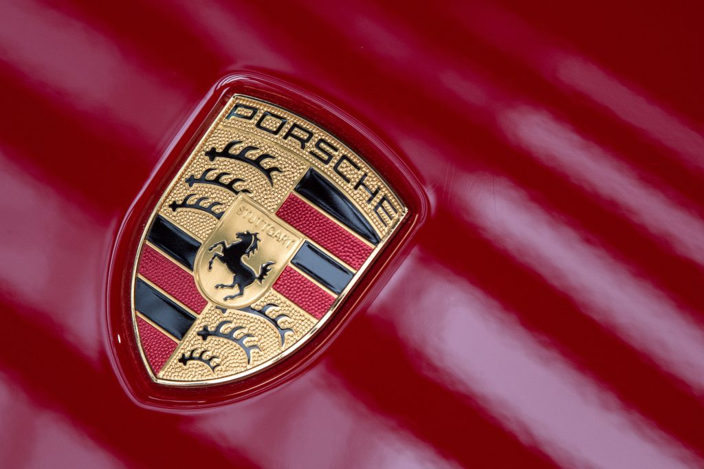 Light reflects off the Porsche logo on a red vehicle