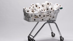 Photo illustration of a pile of unwrapped white toilet paper rolls in a metal shopping cart