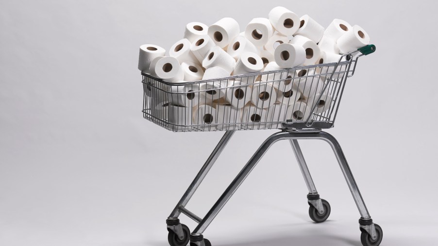 Photo illustration of a pile of unwrapped white toilet paper rolls in a metal shopping cart