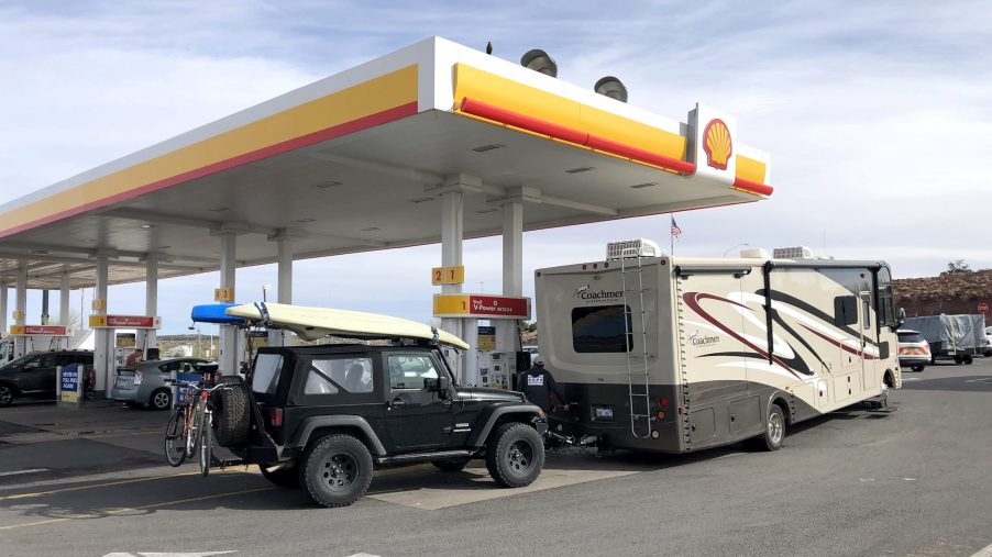 A recreational vehicle stops for gas and is fully prepared for a road trip with an RV, Jeep, Kayak and bicycles