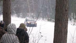 Race spectators in coats and hats at a snowy 2017 SnoDrift Rally forest stage
