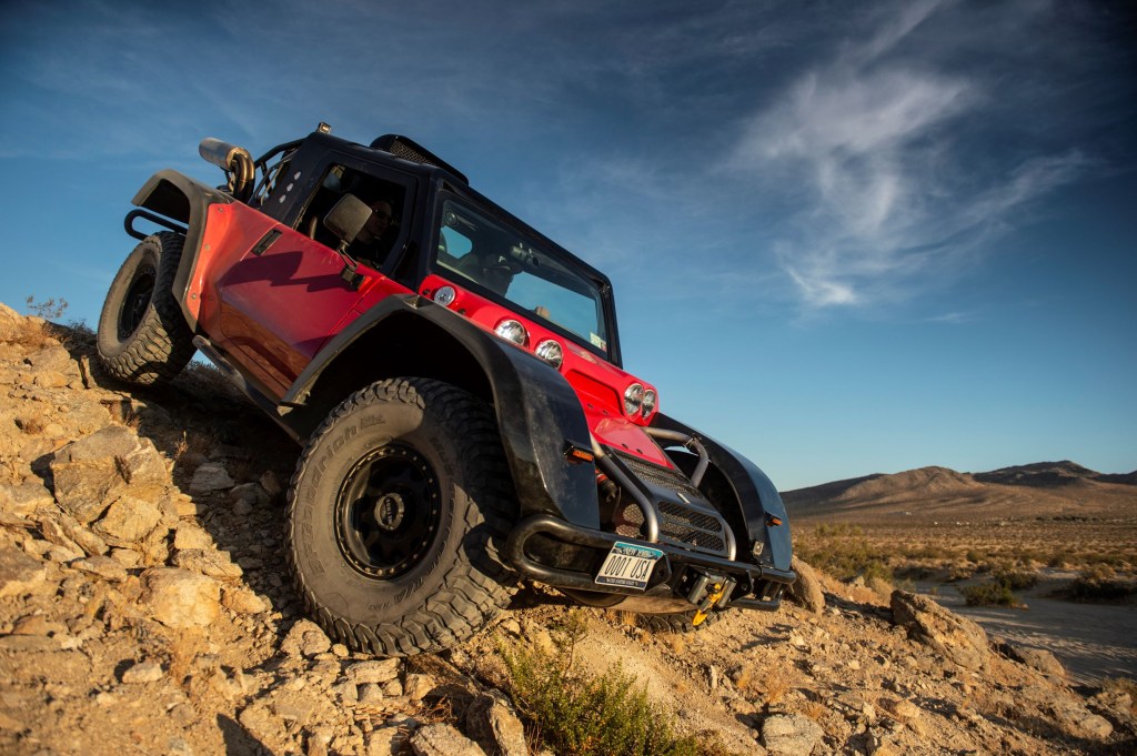 The side 3/4 view of the red-and-black SCG Boot going down a rocky desert hill