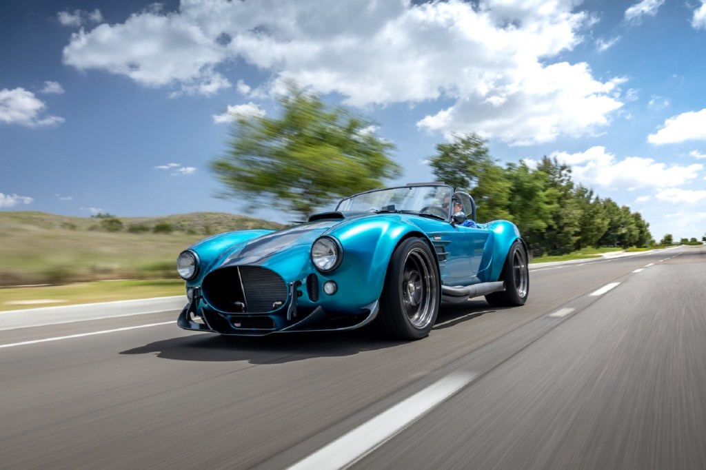 A turquoise-with-silver-stripes Superformance MKIII-R drives down the road